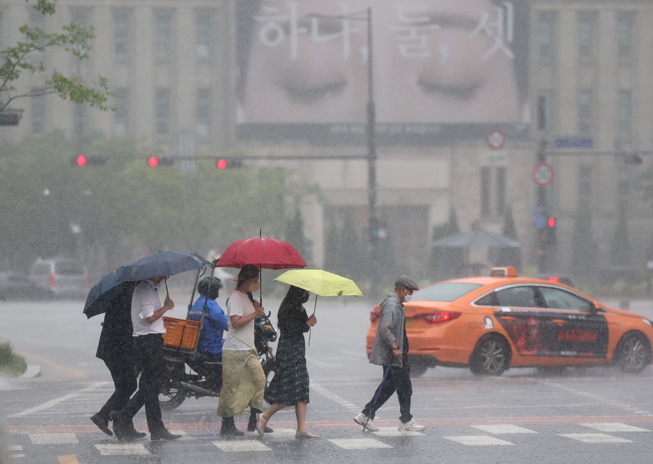 People in umbrellas at a crosswalk in Seoul on Wednesday (Yonhap)