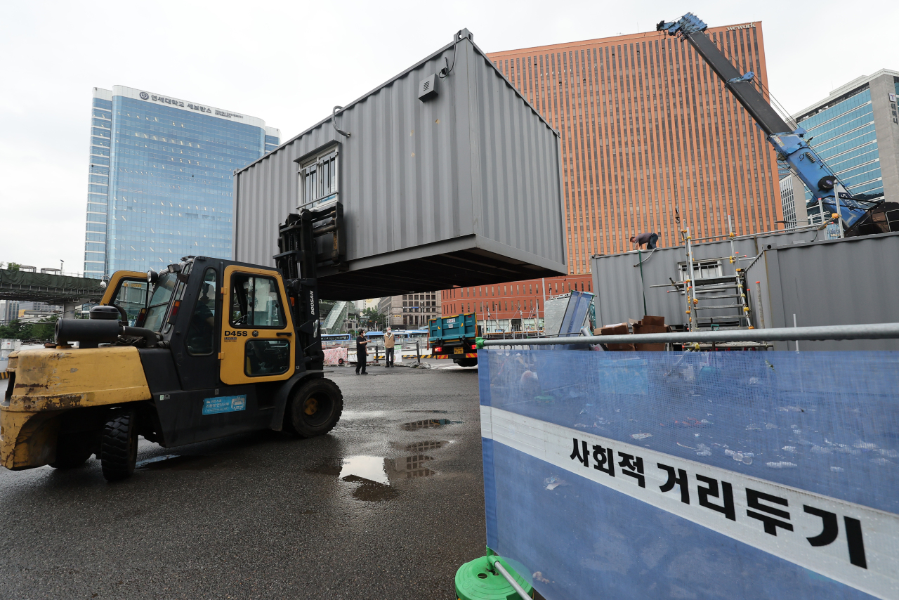 Workers remove a container building used as a makeshift clinic for coronavirus tests in front of Seoul Station on July 1, 2022, as South Korea has seen COVID-19 cases decline in recent weeks. (Yonhap)
