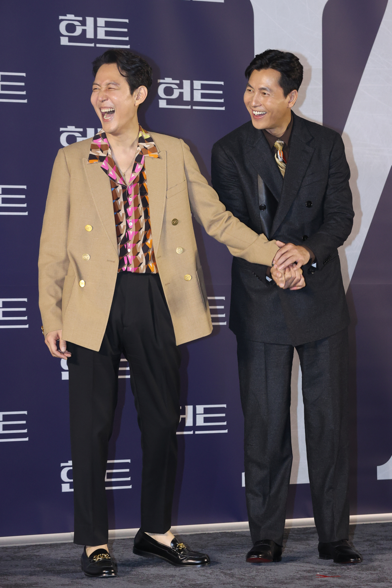 Lee Jung-jae (left) and Jung Woo-sung hold hands during a photo session after a press conference introducing “Hunt” at Megabox Seongsu in Seoul, Tuesday. (Yonhap)