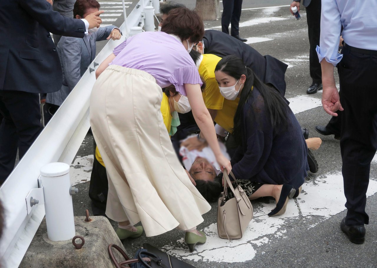 Japan’s former Prime Minister Shinzo Abe, center, falls on the ground in Nara, western Japan Friday, July 8, 2022. Abe was in heart failure after apparently being shot during a campaign speech Friday in western Japan, NHK public television said Friday. (Kyodo News via AP)
