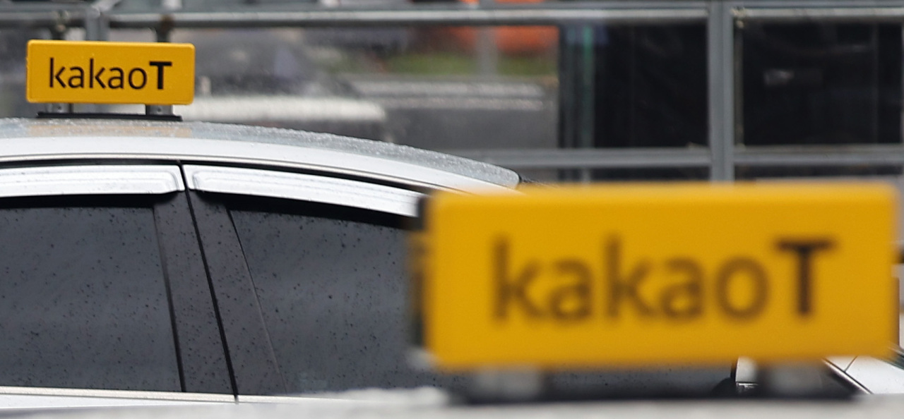 A couple of taxis using Kakao Mobility’s ride-hailing service Kakao T wait for passengers in front of Seoul station on June 28. (Yonhap)