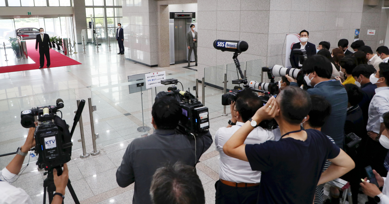 President Yoon Suk-yeol takes reporters' questions from a distance amid a COVID-19 outbreak among the presidential press corps as he arrives at his office in Seoul on Tuesday. (Yonhap)