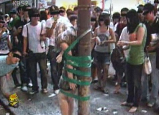 A screenshot of a Sept. 7, 2007, report by KBS shows a person tied to what looks like a street pole or tree with tape and covered in flour. (KBS)