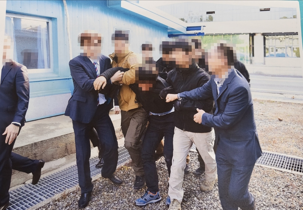 In this photograph released by the Ministry of Unification, North Korean fishermen are apparently being dragged by officials to be handed over to North Korea via the Military Demarcation Line.