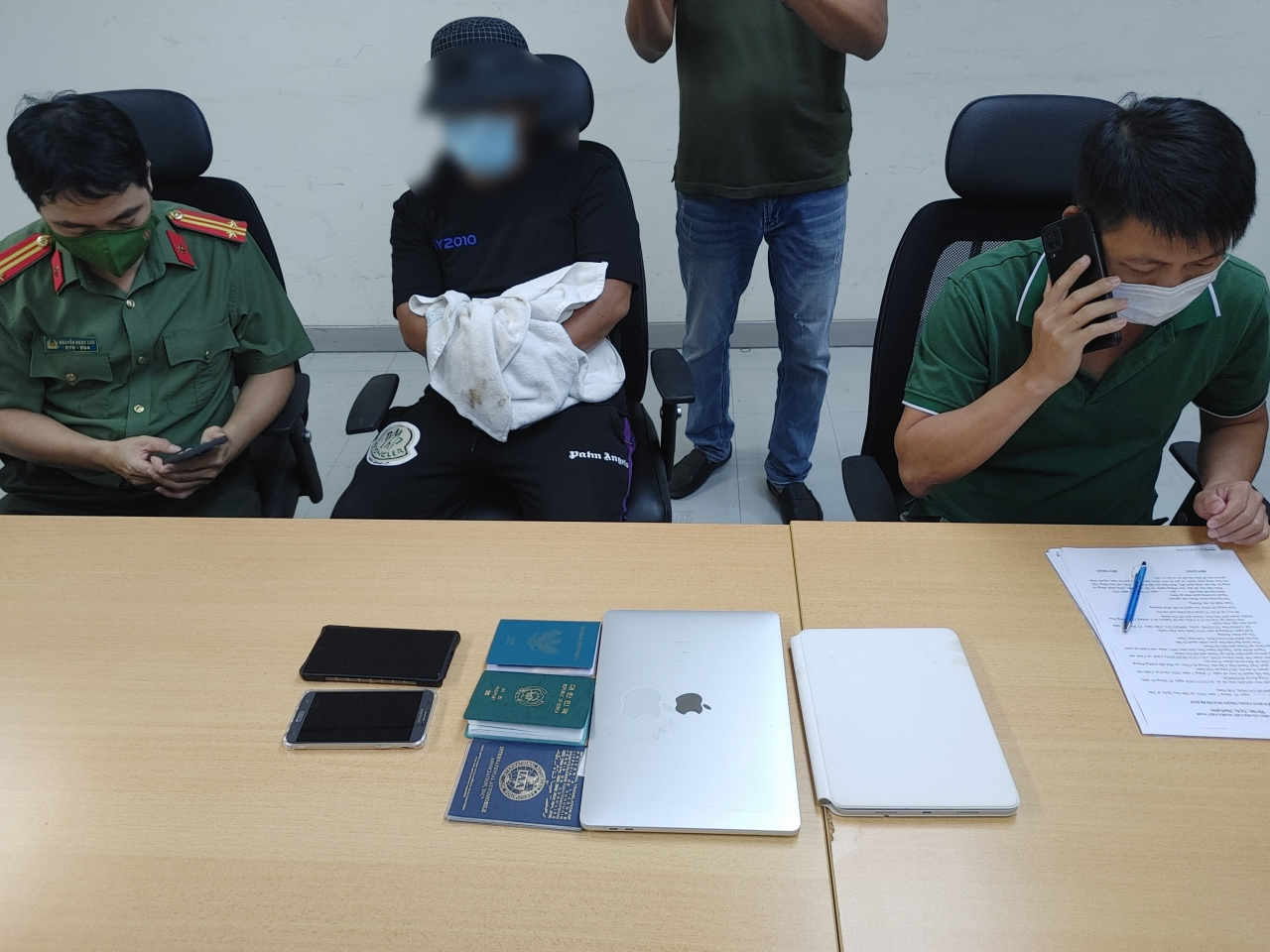 Kim (center) is seen sitting between Vietnamese police officers in Ho Chi Minh on Sunday, prior to being expatriated to South Korea. (National Police Agency)