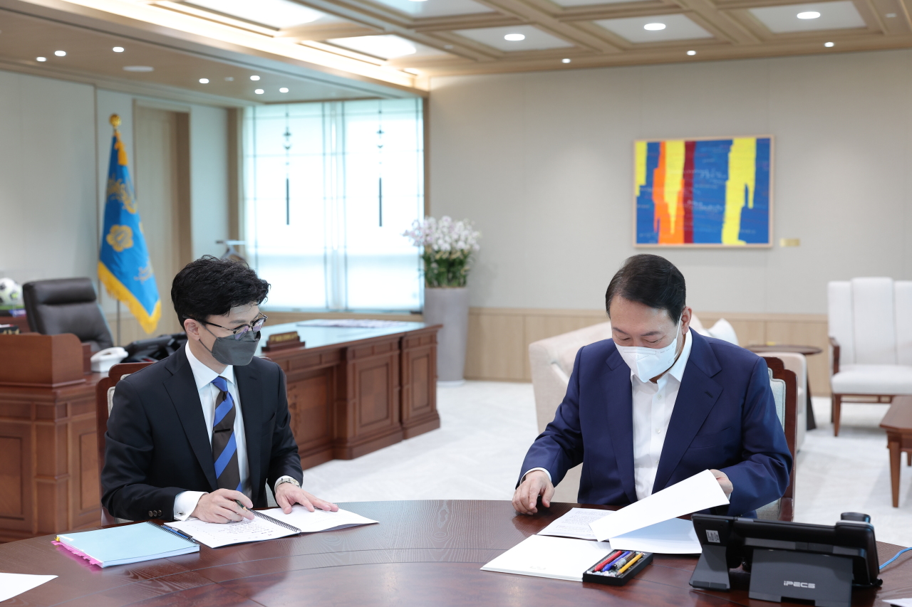 Justice Minister Han Dong-hoon (left) briefs President Yoon Suk-yeol at his office in Yongsan, central Seoul, on Tuesday morning. (Yonhap)