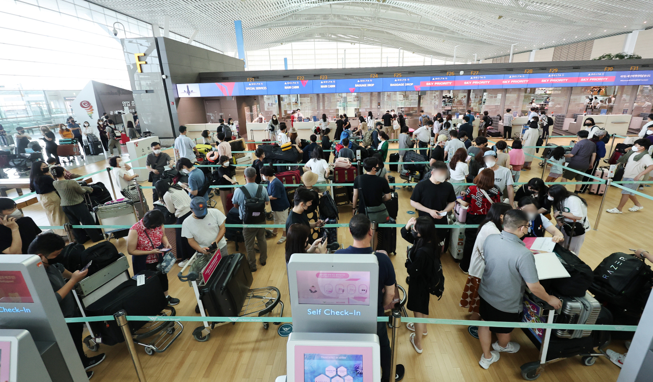Amid another COVID-19 wave Passengers wait in line at Incheon International Airport's international terminal, west of Seoul, July 26. (Yonhap)