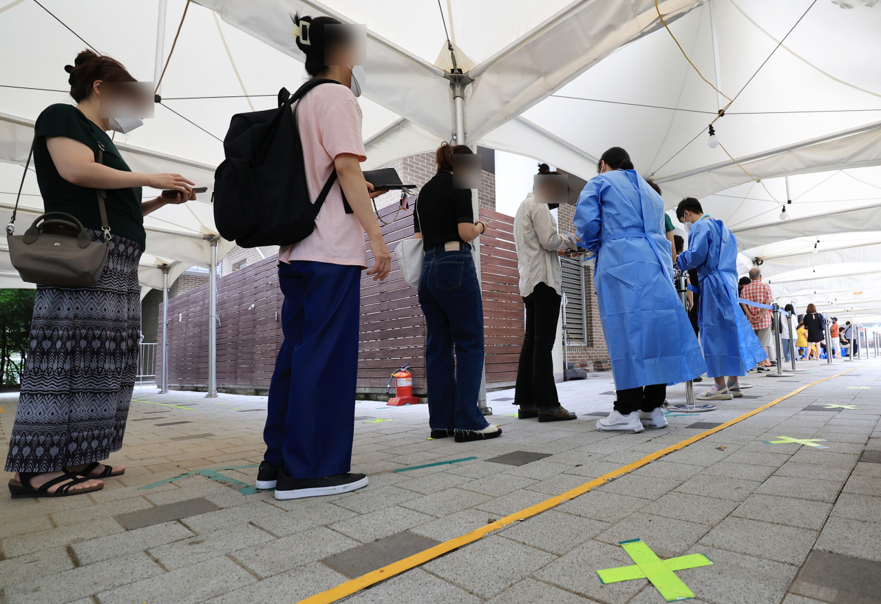 This photo taken on Friday, shows people waiting to take COVID-19 tests at a clinic in Mapo, Seoul. (Yonhap)