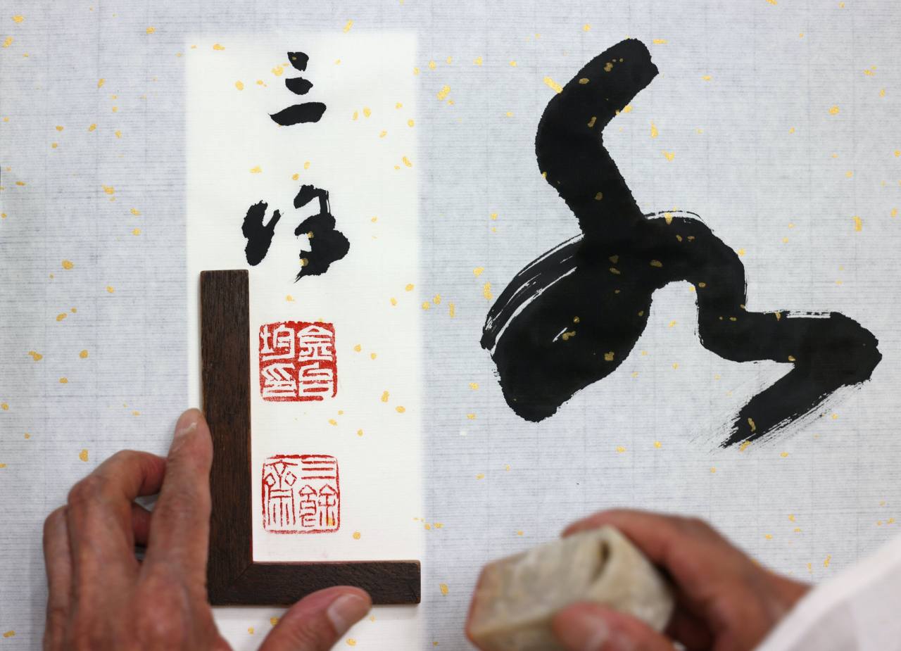 Calligrapher Kim Tae-gyun places his seal on a calligraphy piece. Photo © Hyungwon Kang