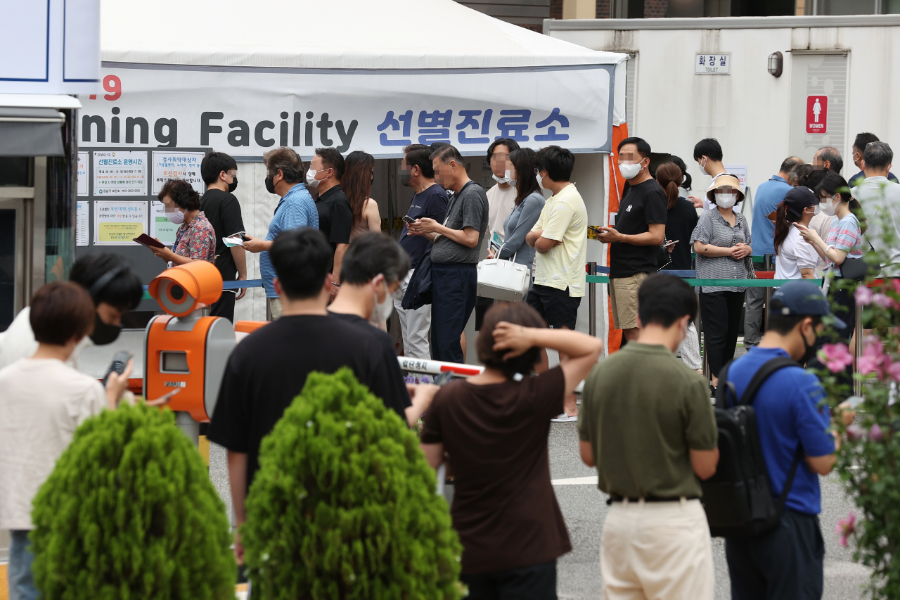 People wait to take coronavirus tests at a COVID-19 testing center in Seoul on Sunday. (Yonhap)