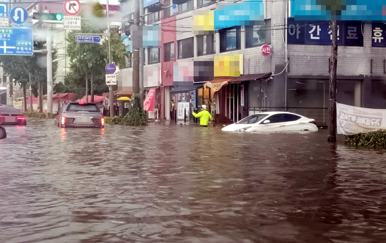 This photo, provided by a reader, shows roads in the western port city of Incheon submerged on Monday. (Yonhap)