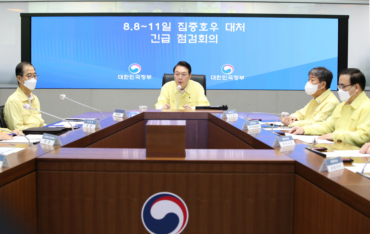 President Yoon Suk-yeol (C) presides over a meeting at the government complex in Seoul on Tuesday, to check damage by torrential rainfall that battered Seoul and surrounding areas the previous night. Over 100 millimeters per hour fell the previous night, the heaviest downpour in 80 years. (Yonhap)