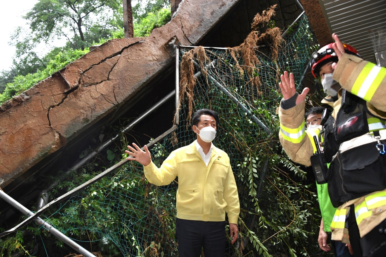 Seoul Mayor Oh Se-hoon is being briefed by a firefighter on the embankment collapse in an apartment complex due to a landslide caused by heavy rainfall, in Sadang-dong, Seoul, Tuesday. (Seoul City Government)