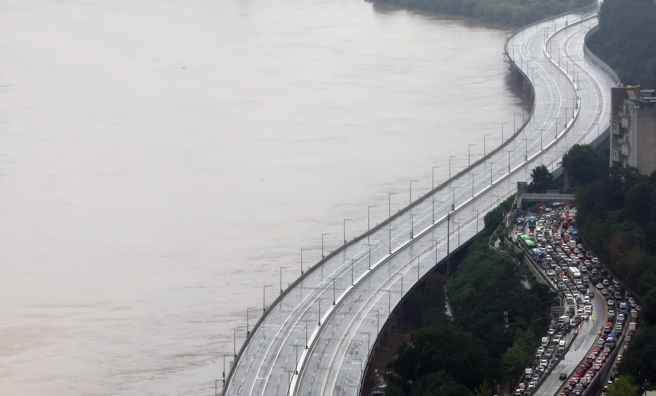 Olympic Highway traffic is controlled on Tuesday morning after the Han River water level rose sharply due to heavy rain on Monday night. (Yonhap)
