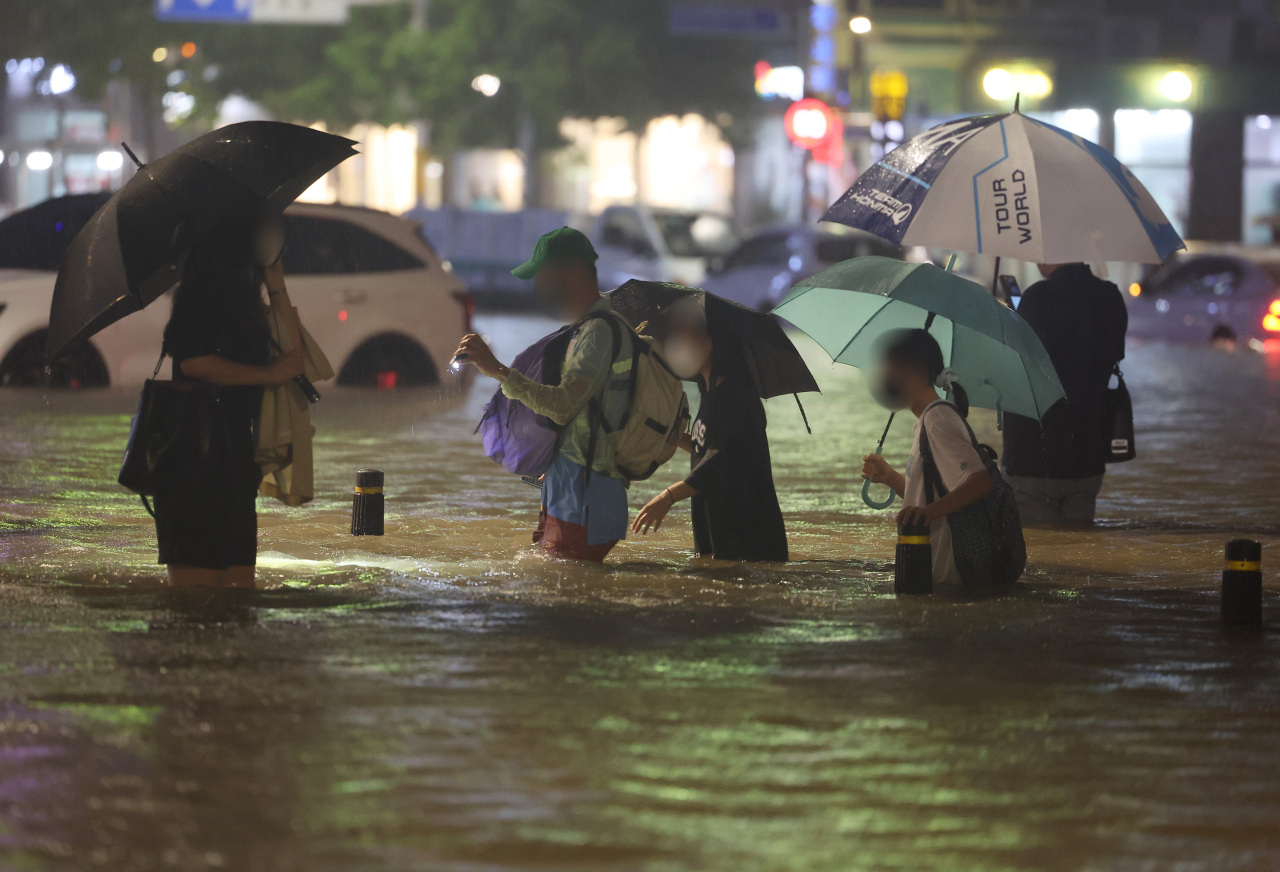 Pedestrians are seen walking near Daechi Station in Gangnam District amid a torrential downpour on Monday night. (Yonhap)