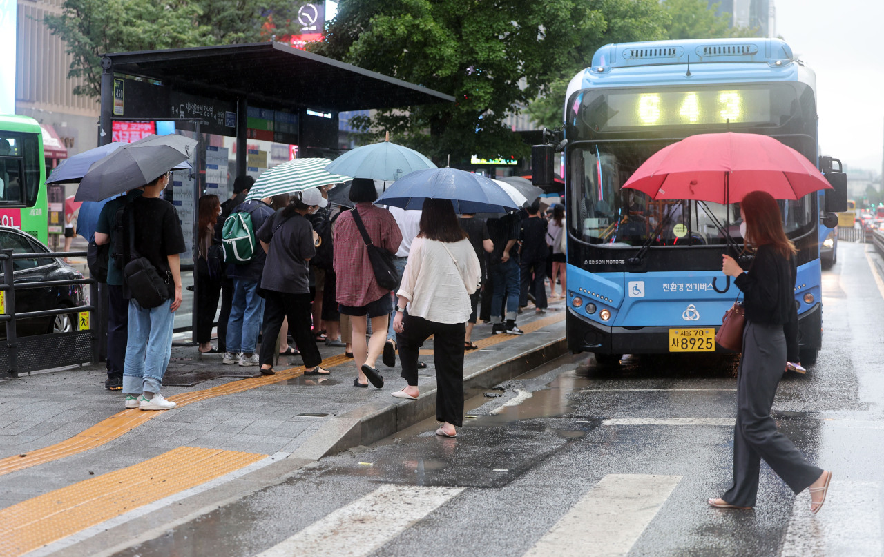 People are standing in line to hop on a city bus in Gangnam-gu, Seoul, on Tuesday morning. (Yonhap)