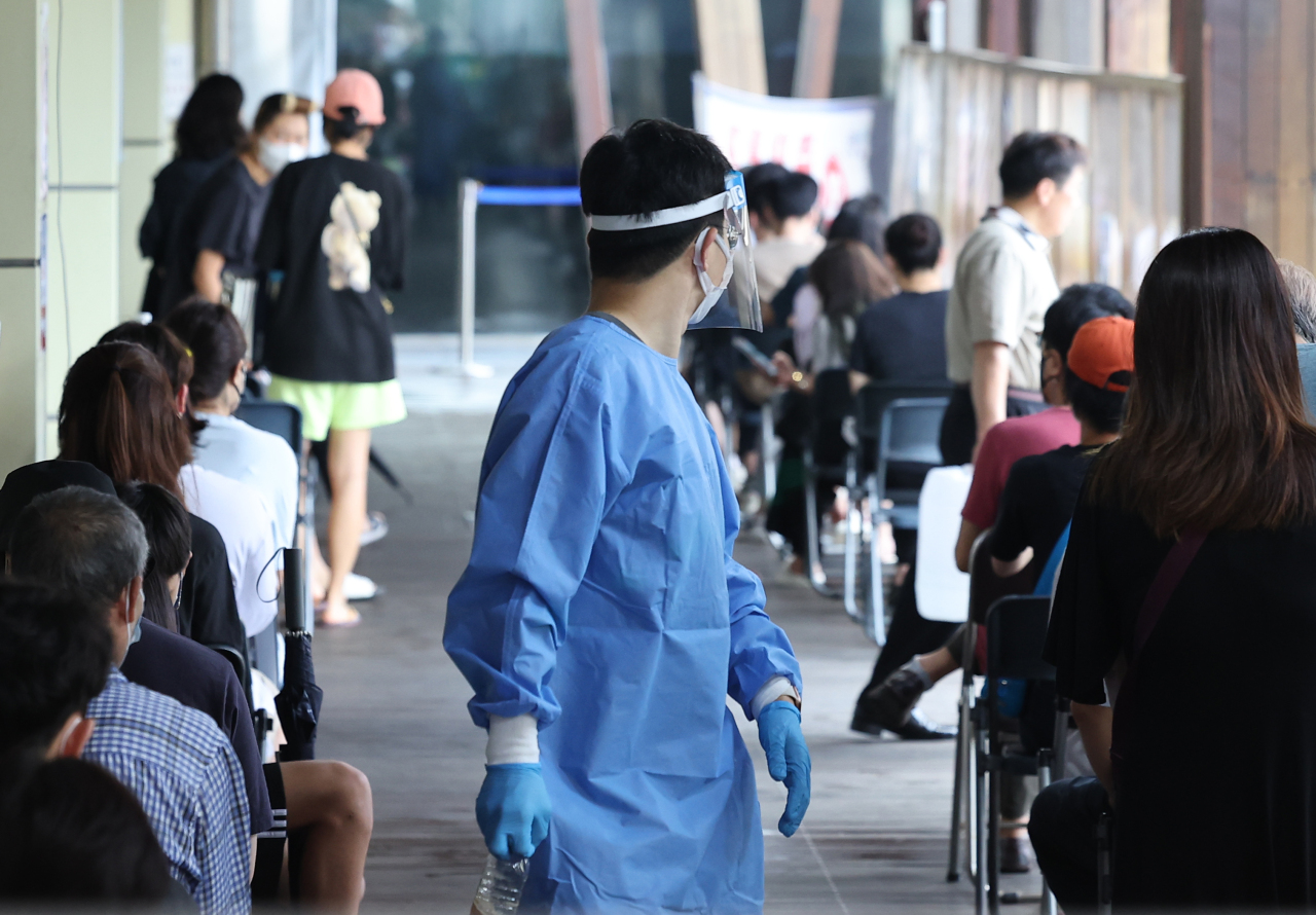 People wait in line for COVID-19 tests at a local testing station in Songpa-gu, Seoul, Wednesday. (Yonhap)