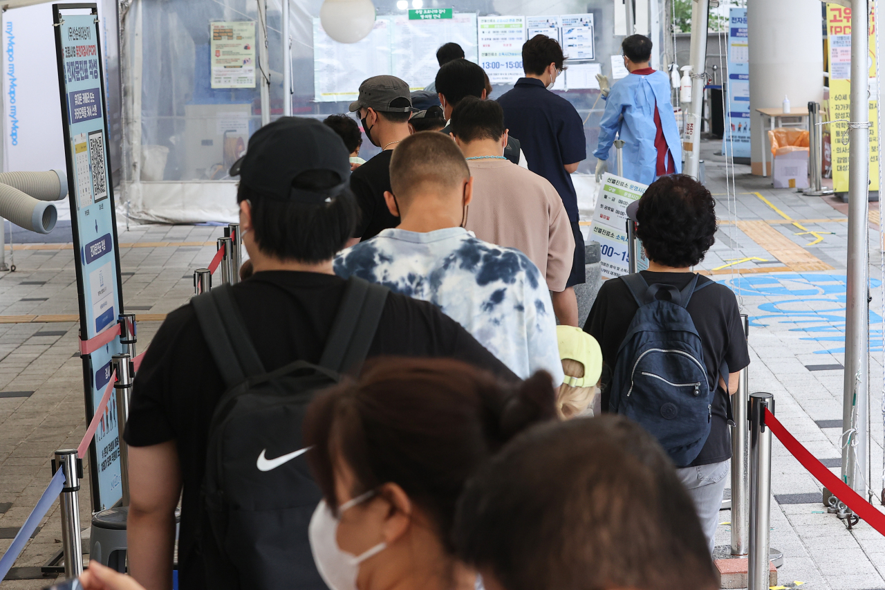 People wait in line to get COVID-19 tests at a testing station located in Mapo-gu, Seoul, Thursday. (Yonhap)