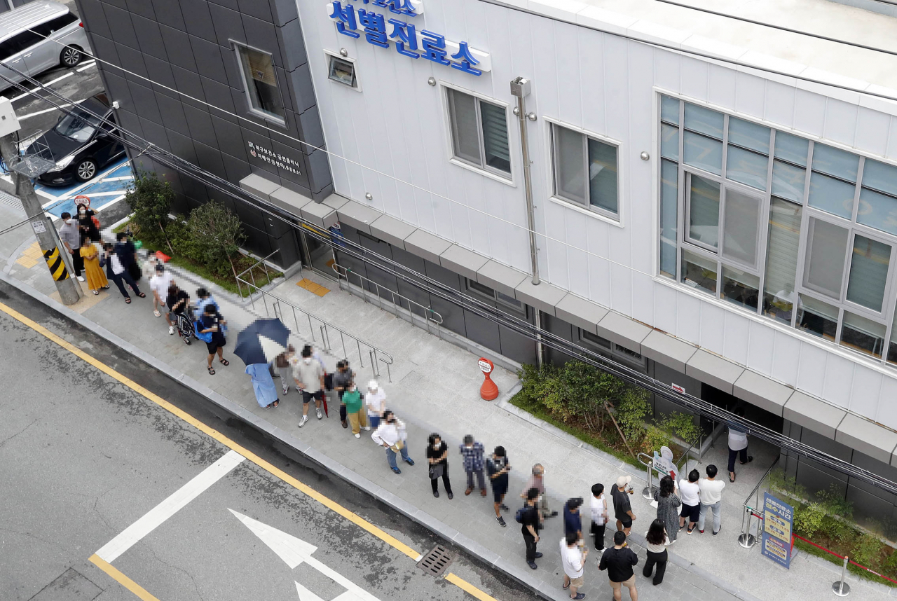 This photo, provided by a ward office in the southwestern city of Gwangju, shows people waiting to undergo COVID-19 tests in the city on Tuesday. (Gwangju ward office)