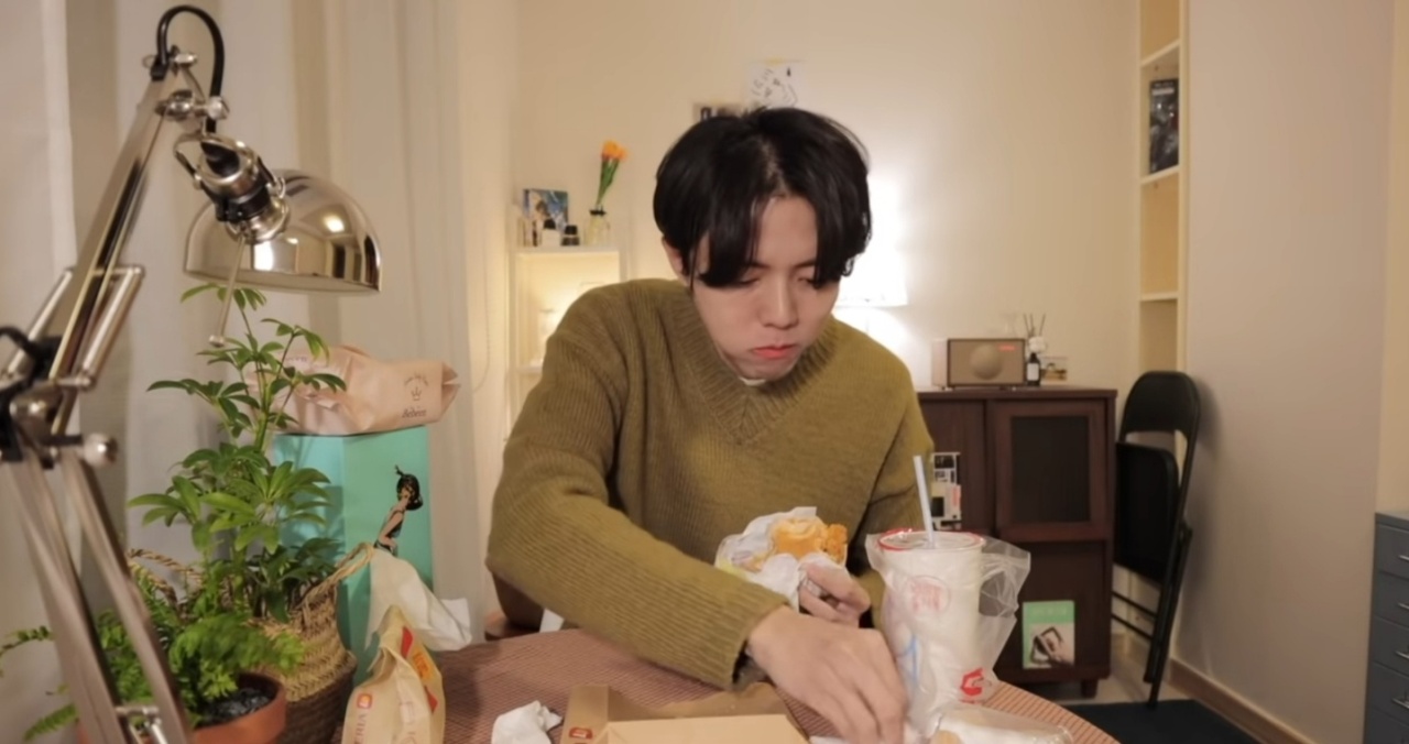 Model Joo Woo-jae eats a burger at a meokbang for his YouTube channel (YouTube)