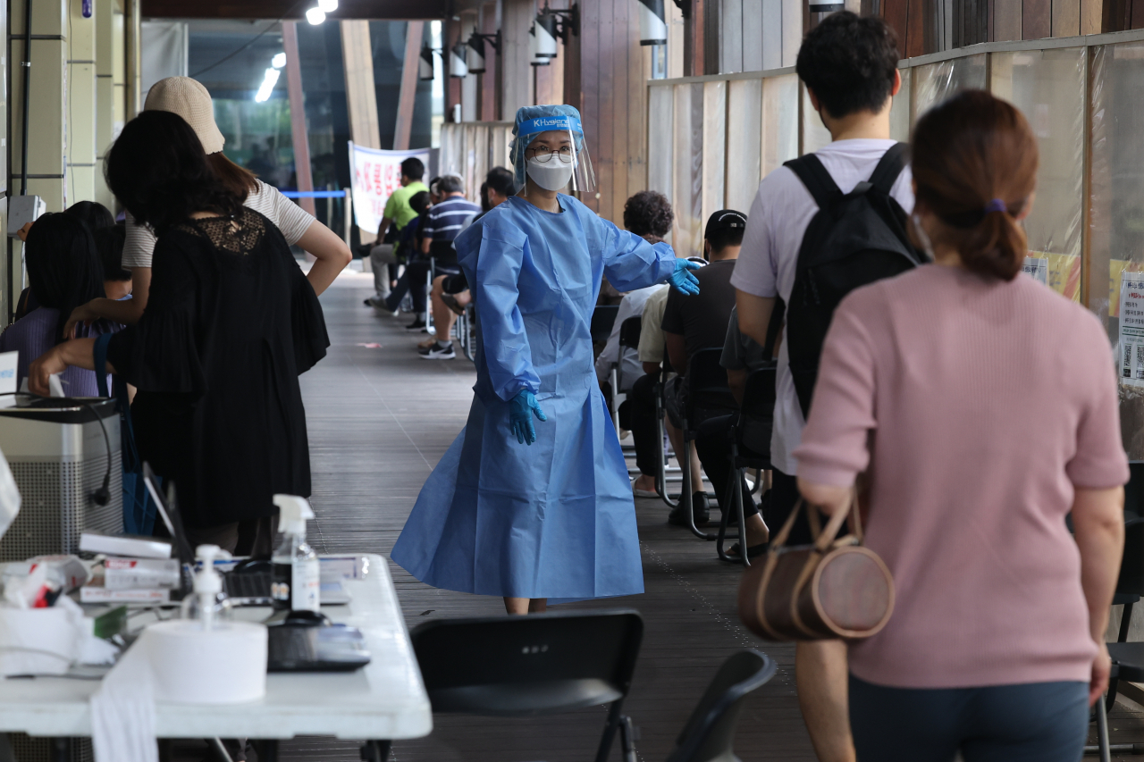 People line up at a COVID-19 testing center in Seoul on Sunday. (Yonhap)