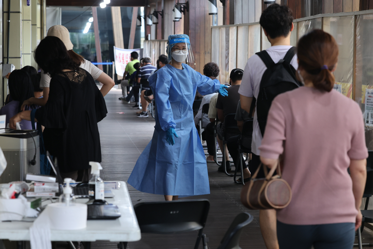 People line up at a COVID-19 testing center in Seoul last Sunday. (Yonhap)