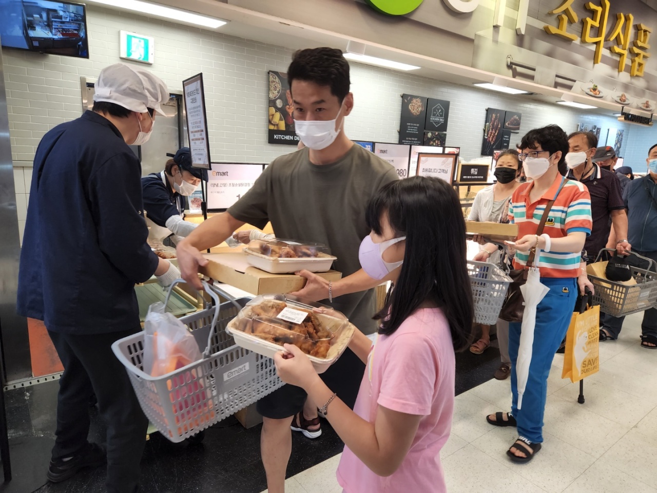 People receive buckets of fried chicken at a deli counter on the basement floor of an E-mart in Eunpyeong-gu, northern Seoul, on Tuesday. (Choi Jae-hee / The Korea Herald)