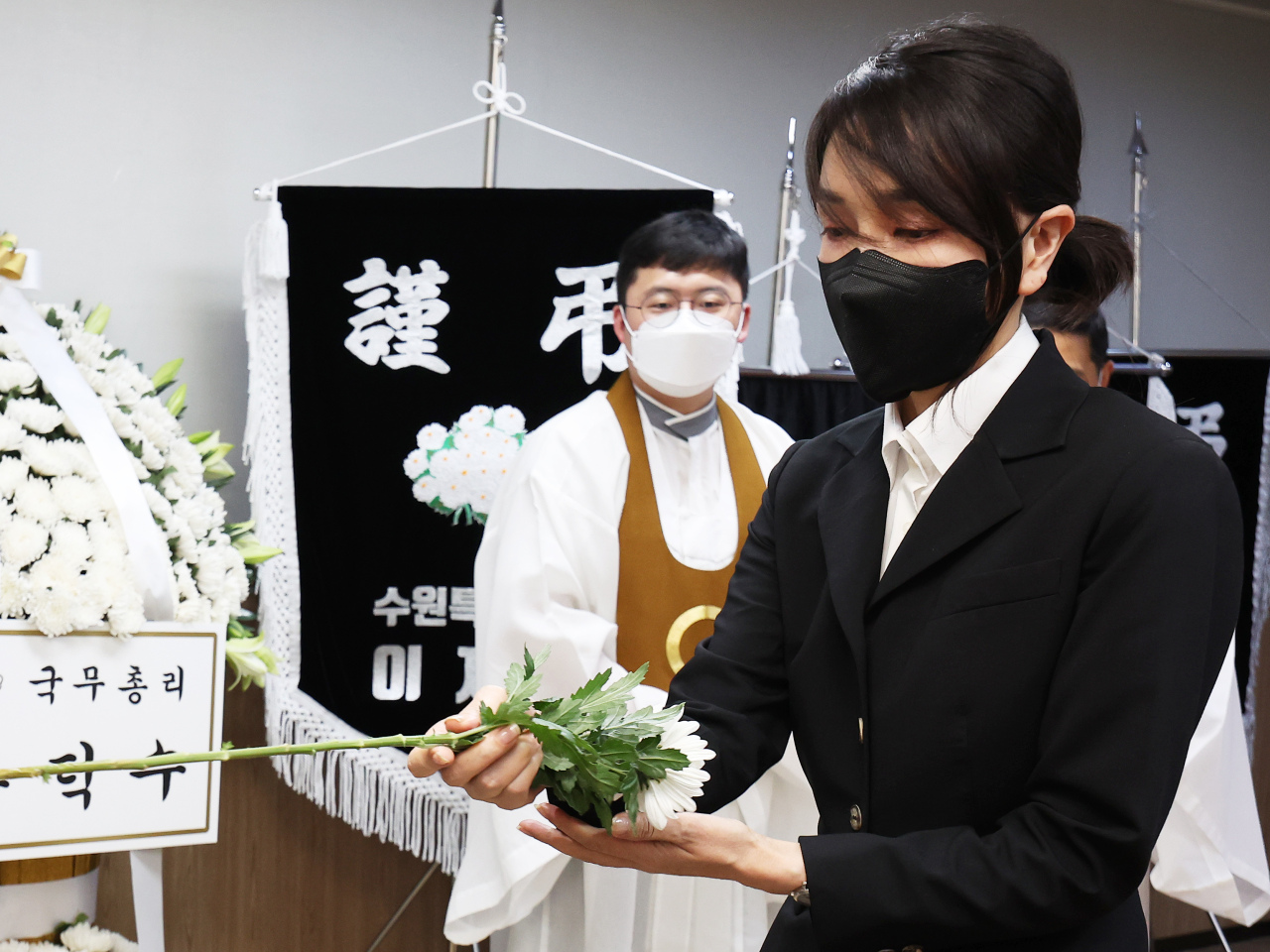 First lady Kim Keon-hee lays flowers on the altar during her visit Thursday to the funeral house in Suwon, Gyeonggi Province, where the public funeral for the mother and her two daughters is being held. (Yonhap)