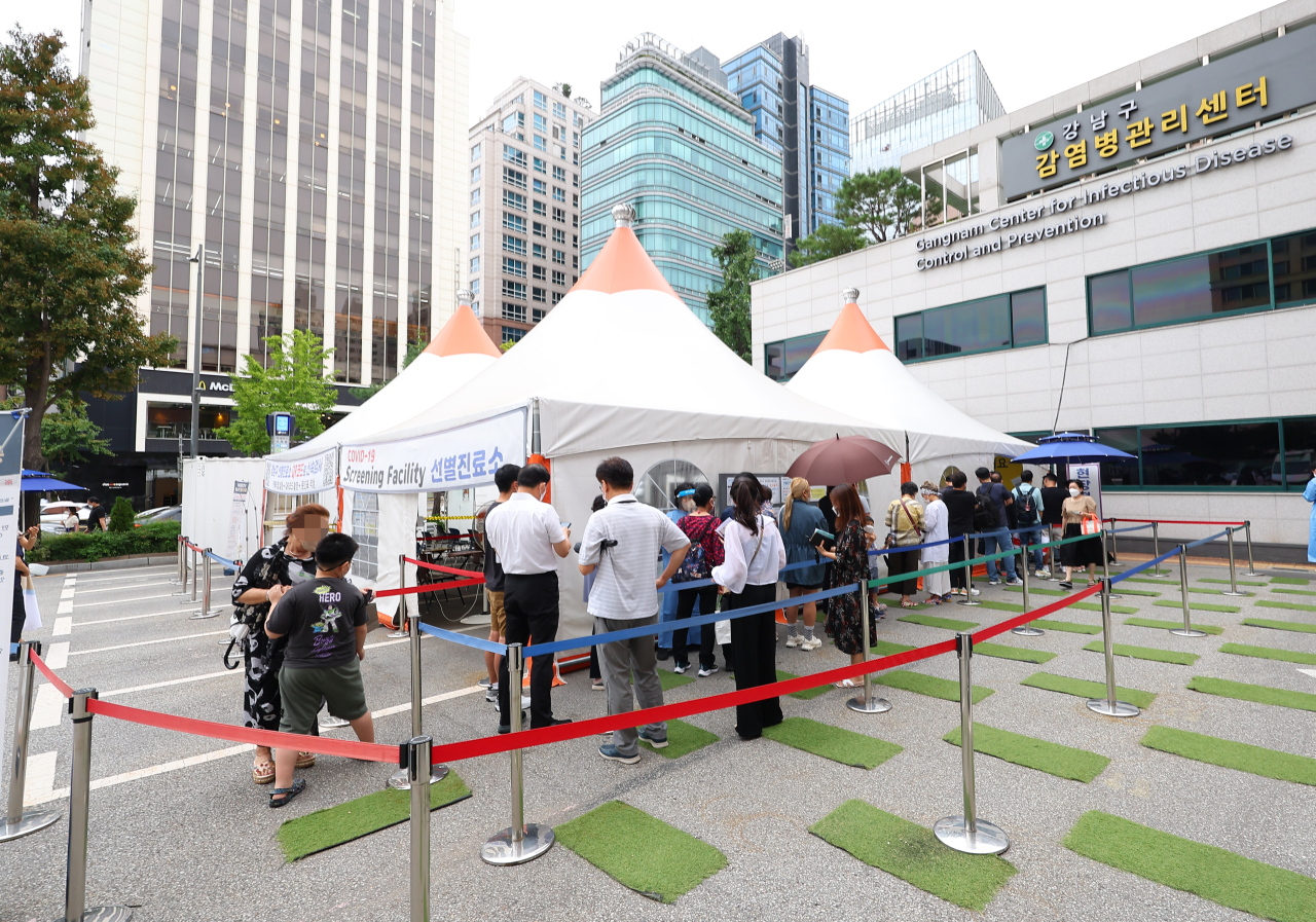 People line up in front of a COVID-19 testing booth in southern Seoul on Thursday. (Yonhap)