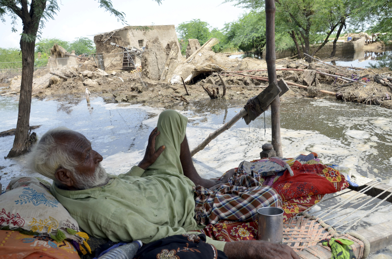 A man rests near his damaged home surrounded by floodwaters, in Jaffarabad, a district of Pakistan's southwestern Baluchistan province, on Sunday. (AP-Yonhap)