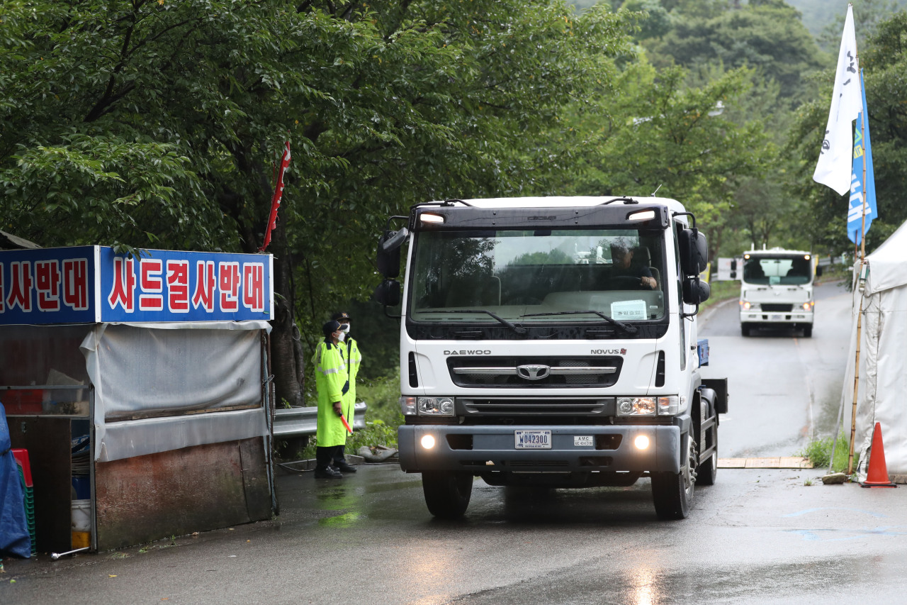 Vehicles come and go on the driveway of the THAAD base in Seongju, North Gyeongsang Province, Aug. 16. A banner that reads 