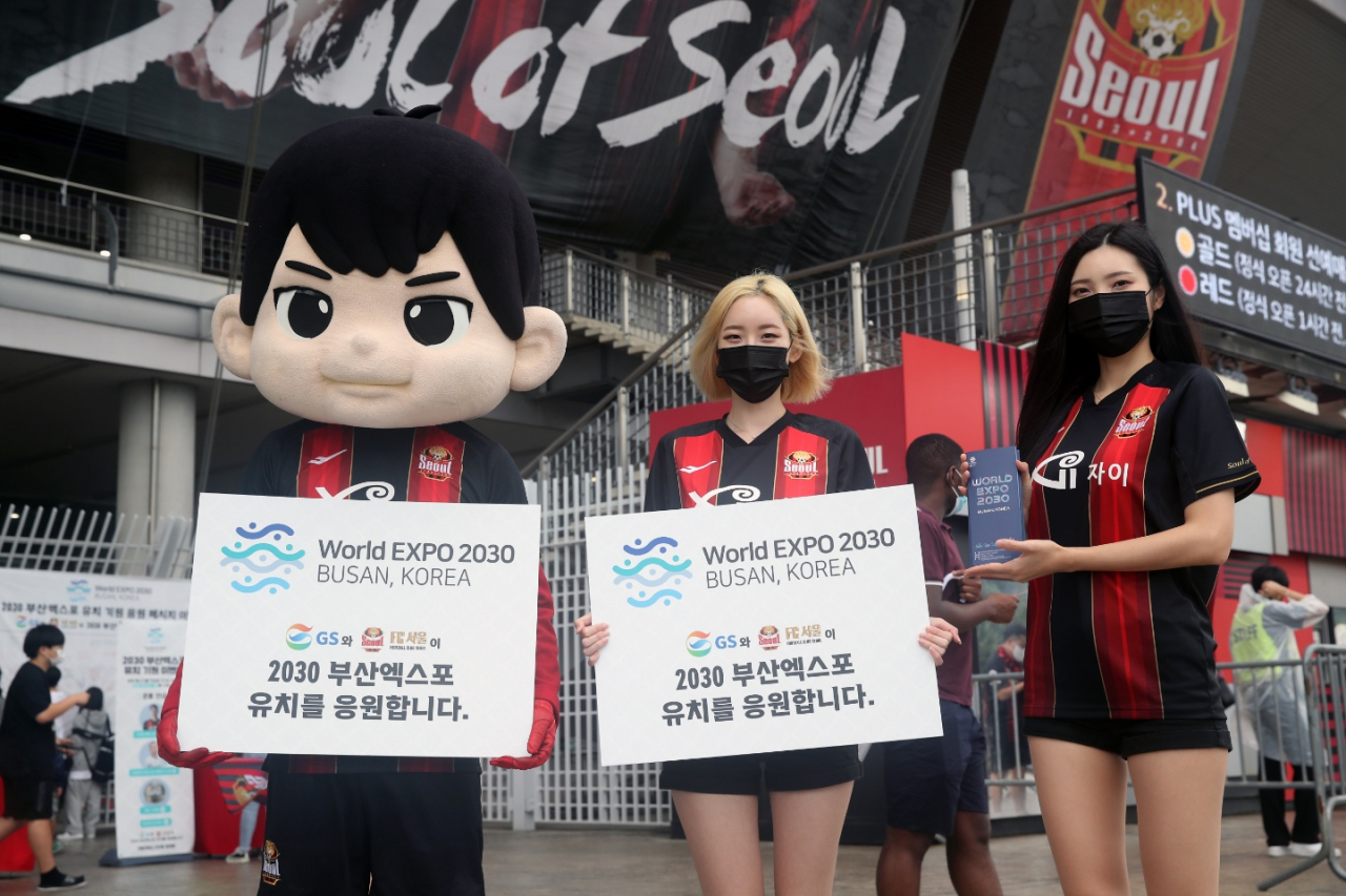 Fans pose with promotional placards to support the 2030 Busan Expo bid during a football match between FC Seoul and Suwon Samsung held at Seoul World Cup Stadium in Seoul on Sunday. (GS Group)
