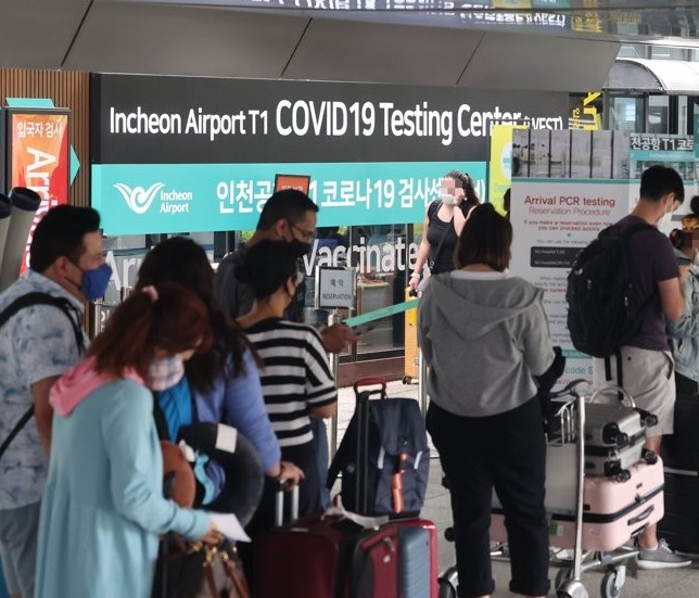 Travelers from abroad stand in line to take coronavirus tests at a testing station at Incheon International Airport last Wednesday.