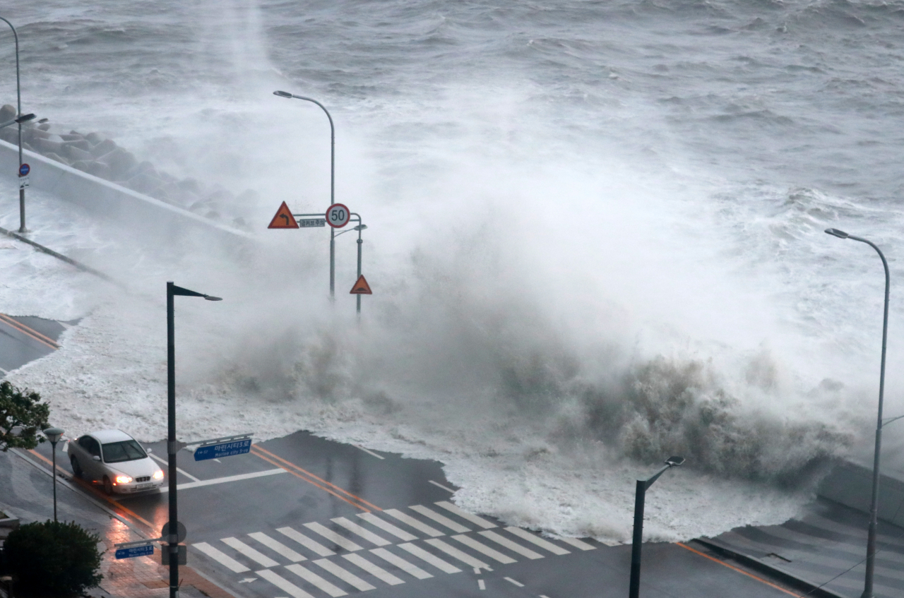A high tide wave hits a coastal road near Marine City in Busan.