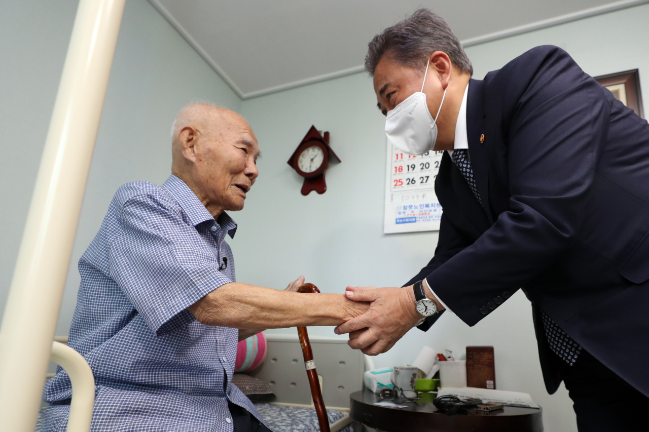 South Korean Foreign Minister Park Jin holds hands of Lee Choon-sik, 98-year-old survivor of wartime forced labor, in Gwangju on Friday. (Yonhap)