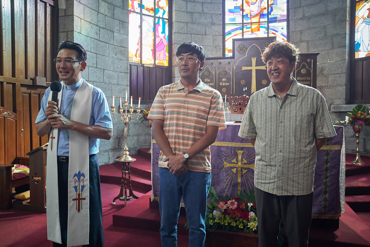 A still image shows Hwang Jung-min (left) as Pastor Jeon and Ha Jung-woo (center) as Kang In-gu at a church in 
