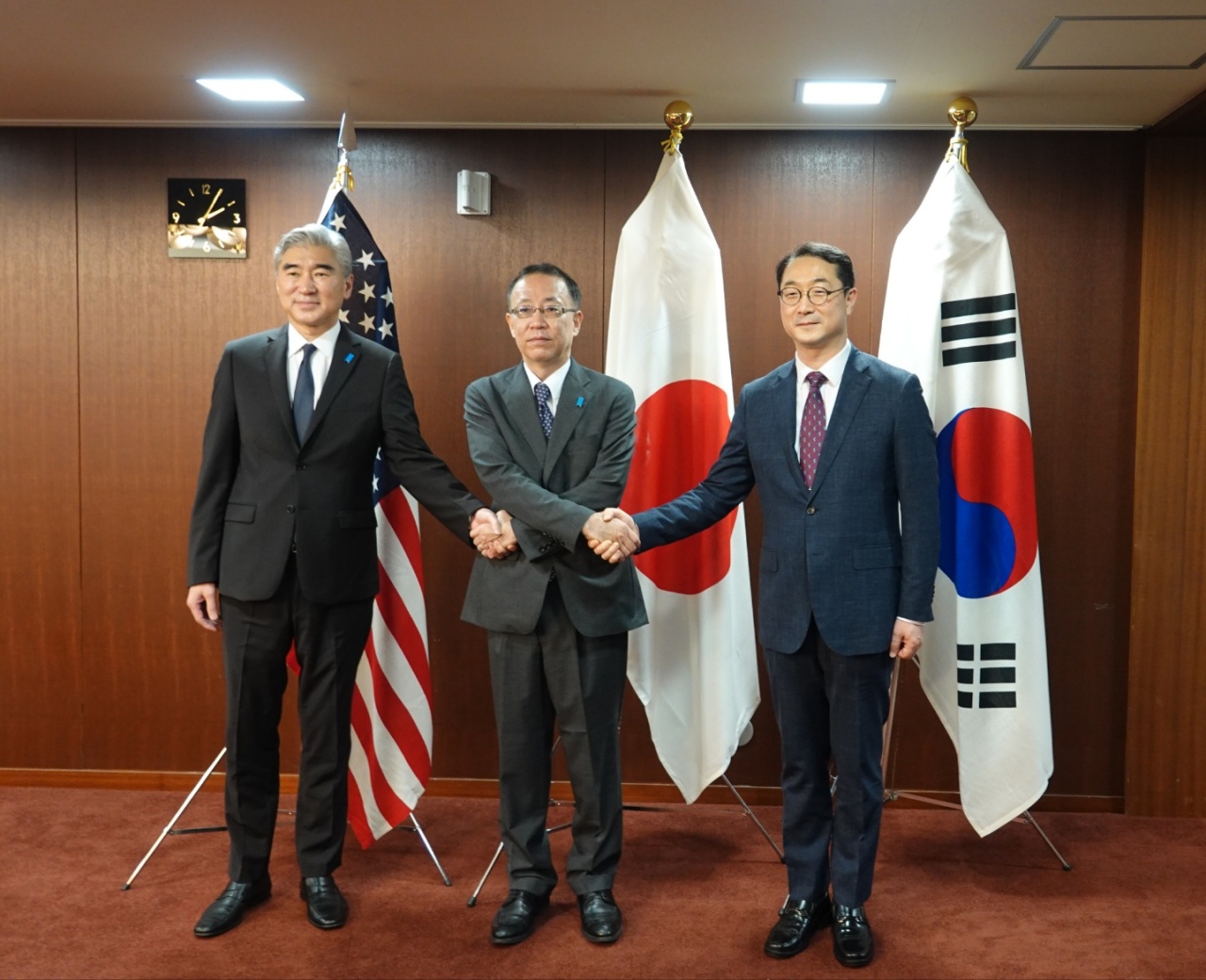 Kim Gunn, Seoul's special representative for Korean Peninsula peace and security affairs (right), hold hands with Sung Kim, Washington's special representative for North Korea (left), and Takehiro Funakoshi, director general for Asian and Oceanian affairs at Japan’s Foreign Ministry before their trilateral talk at the Japanese Foreign Ministry in Tokyo, Japan, Wednesday. (Yonhap)