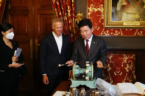 This photo, provided by National Assembly Speaker Kim Jin-pyo's office on Wednesday, shows the parliamentary speaker (right) demonstrating a traditional Korean instrument he presented as a gift to Ander Gil Garcia, president of the Senate of Spain, during their meeting in Spain. (Yonhap)
