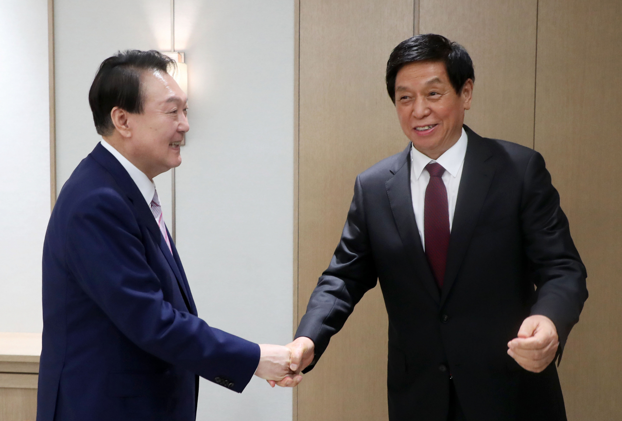 South Korean President Yoon Suk-yeol (left) shakes hands with China's top legislator Li Zhanshu during a meeting at the presidential office in Seoul on Friday. (Yonhap)