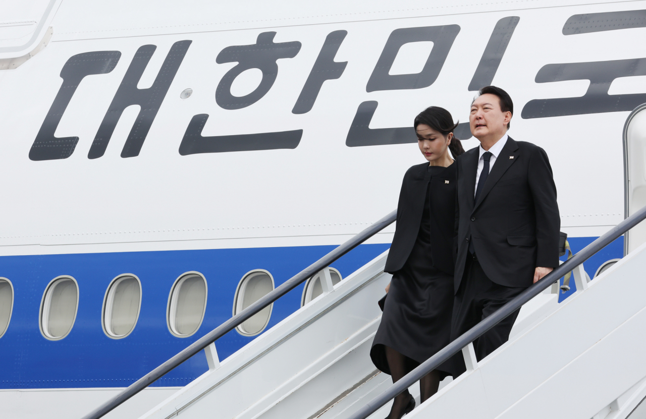 President Yoon Suk-yeol (R) and first lady Kim Keon-hee arrive in London on Sunday, to attend the state funeral of Queen Elizabeth II. (Yonhap)