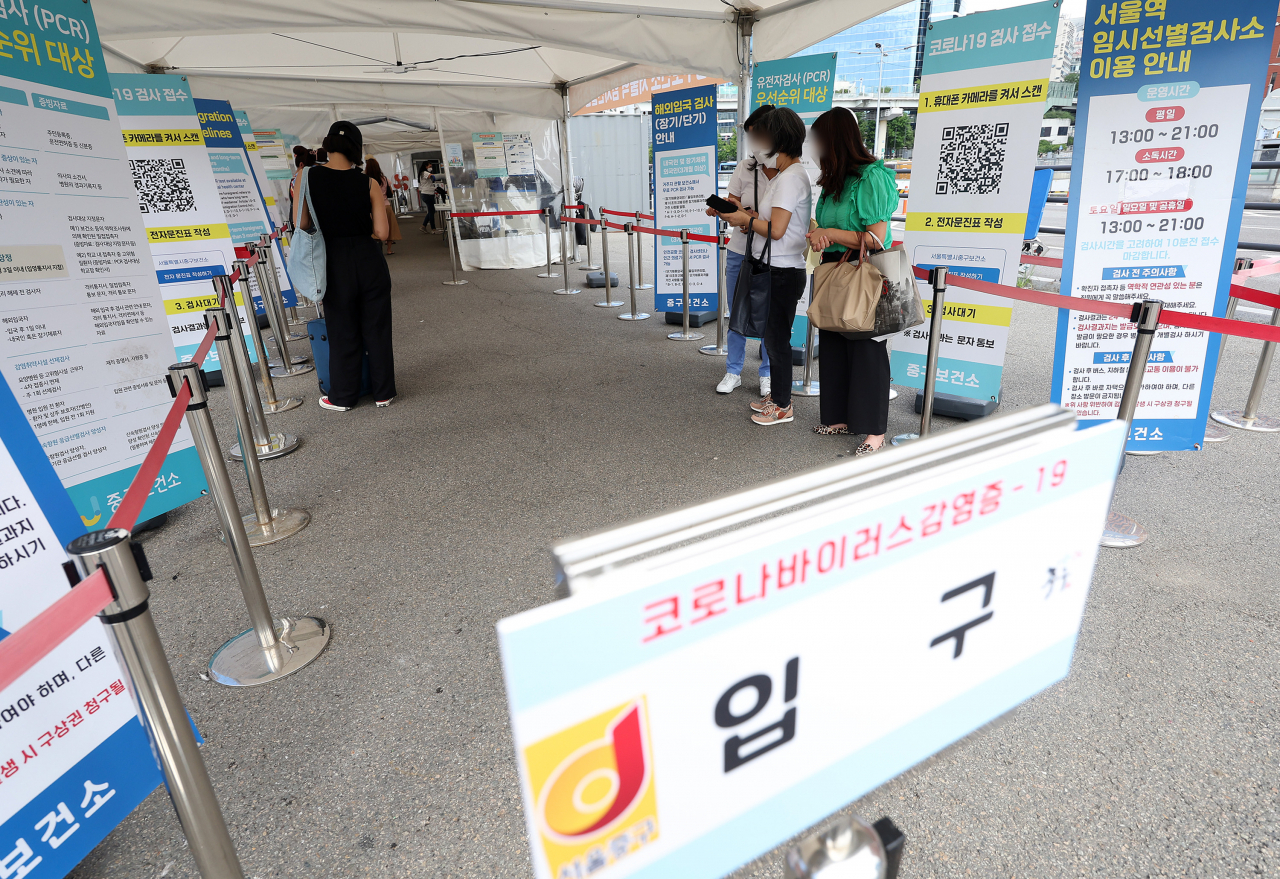 People wait to get tested for COVID-19 at a testing center in central Seoul on Sunday. (Yonhap)