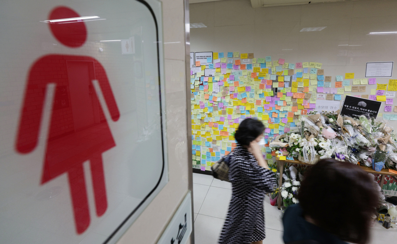 Flowers and messages are left by mourners outside the women’s bathroom in Sindang station, where a 28-year-old woman was stabbed to death by her stalker on Sept. 14. (Yonhap)