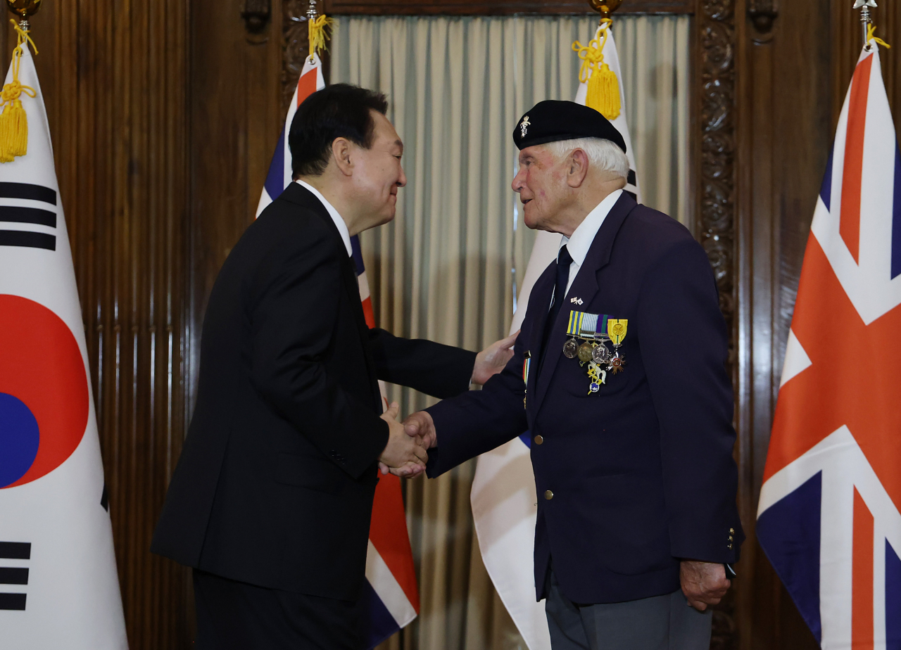 President Yoon Suk-yeol (L) shakes hands with Victor Swift, a British Korean War veteran, after presenting him with the Civil Merit Medal at a hotel in London on Monday. (Yonhap)