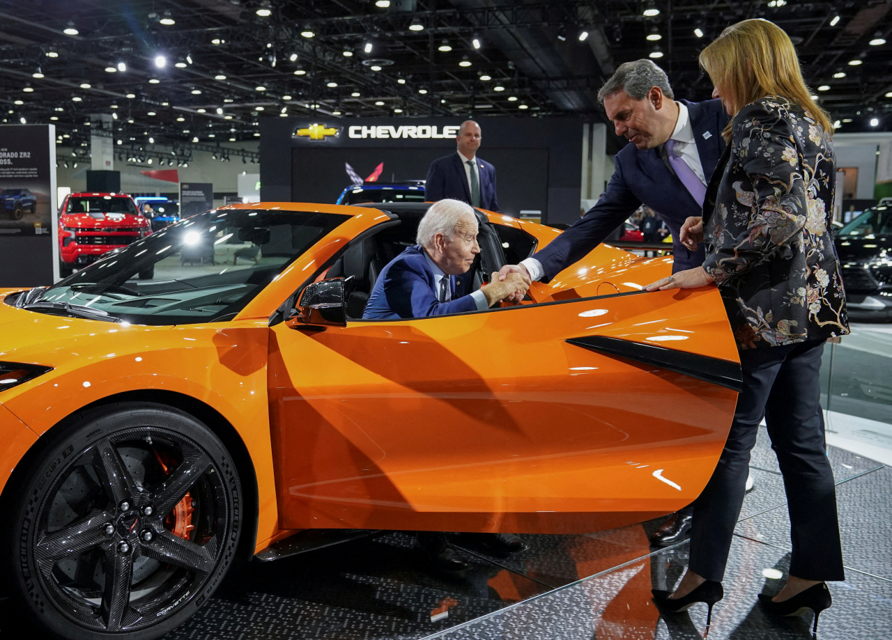 US President Joe Biden is helped out of a Chevrolet Corvette Z06 by General Motors President Mark Reuss as GM CEO Mary Barra looks on during a visit to the Detroit Auto Show to highlight electric vehicle manufacturing on Sept. 14. (Reuters-Yonhap)