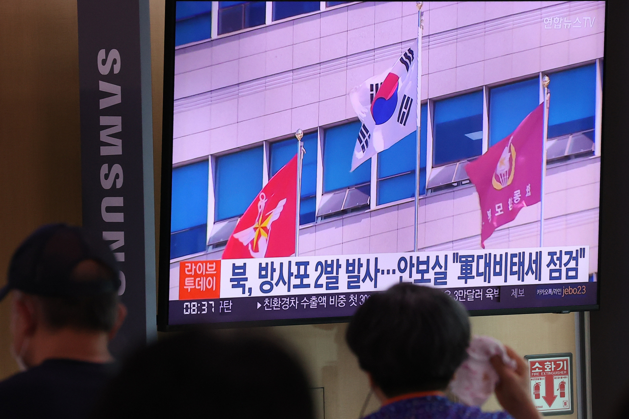 Passersby watch a television news report on North Korea's firing of suspected artillery shots at Seoul Station in the capital city on July 11. (Yonhap)