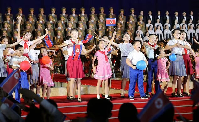 This screengrab of North Korea's celebrations of its 74th founding anniversary, broadcast on Korea Central News Agency, shows a child speculated to be the only daughter of North Korean Kim Jong-un. (The child in the center, wearing the pink dress with the hair down and holding the North Korean flag above her head) (Korea Central News Agency)