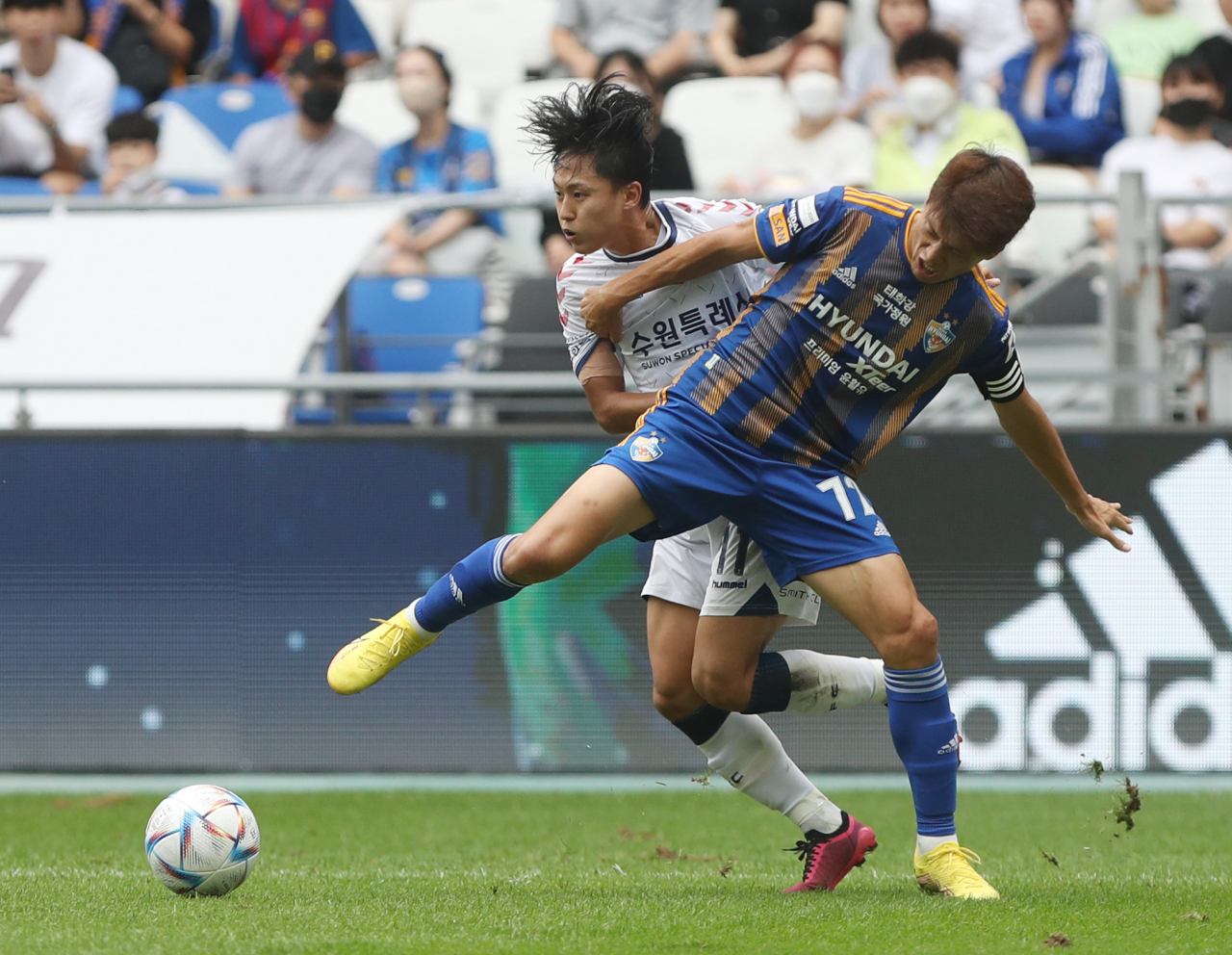 In this file photo from Sept. 18, Lee Chung-yong of Ulsan Hyundai FC (R) and Lee Seung-woo of Suwon FC battle for the ball during the clubs' K League 1 match at Munsu Football Stadium in Ulsan, 380 kilometers southeast of Seoul. (Yonhap)
