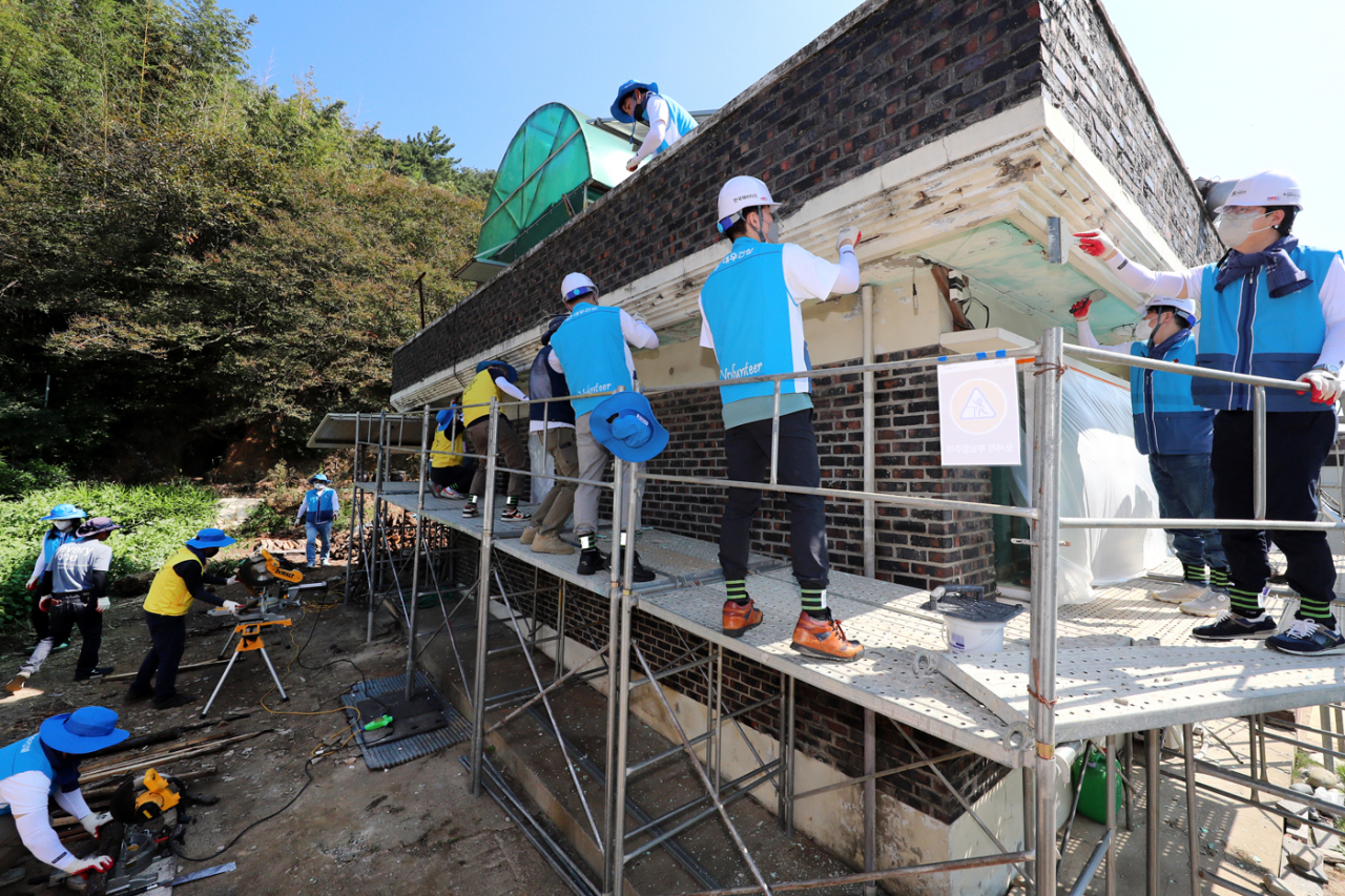 Daewoo E&C and Jungheung Group employees work on renovating an old house of a patriot descendent in Gwangju on Friday. (Daewoo E&C)