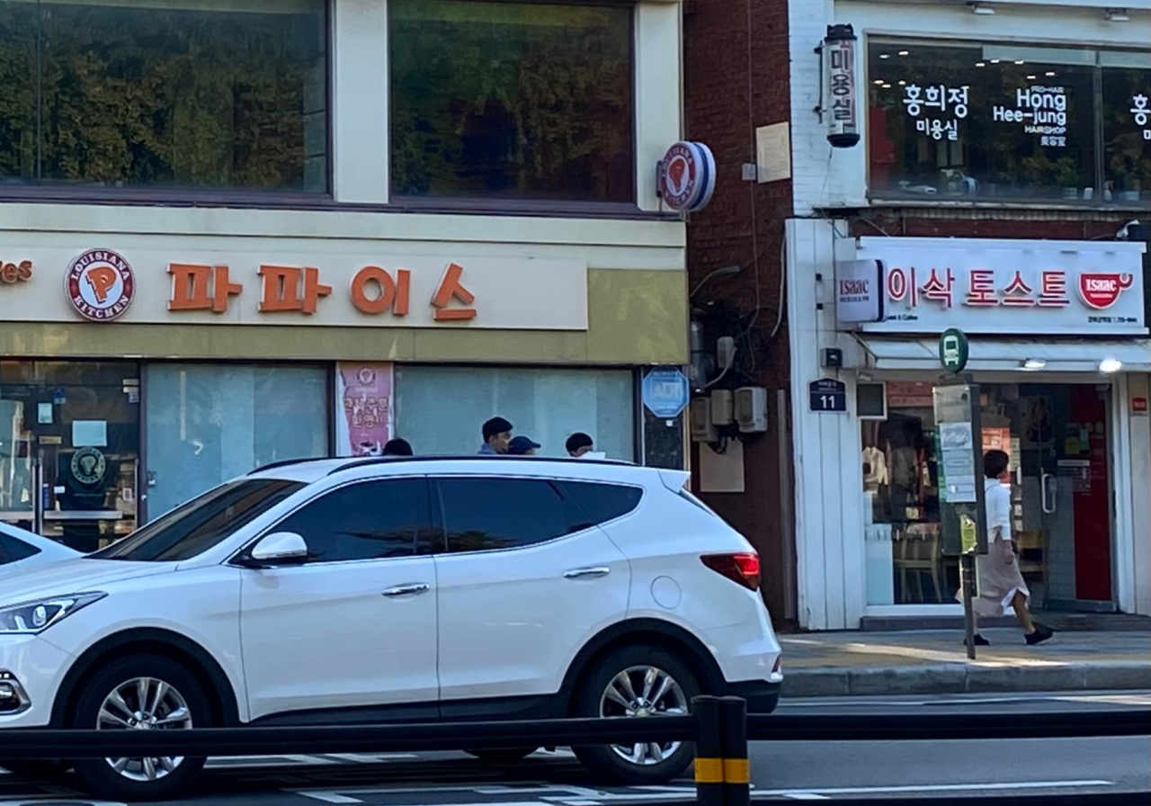 Hangeul signboard of Popeyes restaurant, which closed in 2018, and Issac Toast are seen near Gyeongbokgung Station in central Seoul, last week. (Lim Jae-seong/The Korea Herald)