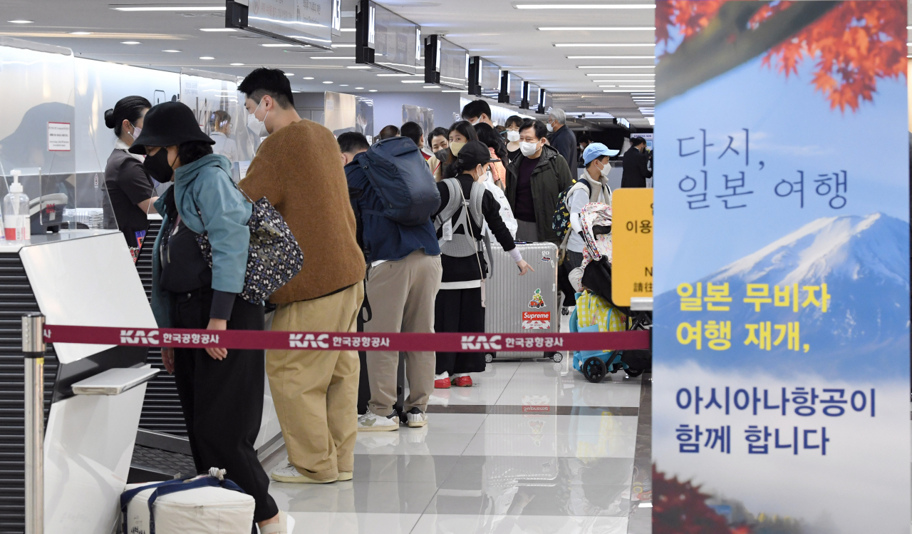 Tourist wait in line to receive tickets for Japan at Gimpo International Airport, Seoul, Tuesday. The banner on the right reads 